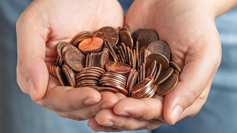 A close up of two hands full of pennies