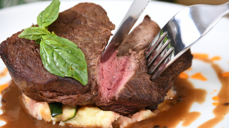 knife and fork cutting into steak