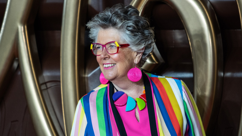 Chef Prue Leith wearing a colorful outfit, looking to the side, and smiling
