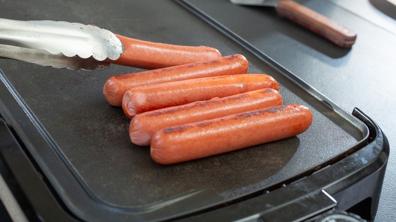 Hot dogs cooking on a griddle