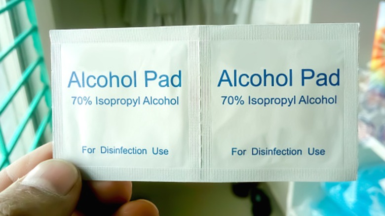 Person holding two alcohol pads in packaging