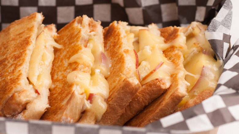 A grilled cheese sandwich with slices of apple inside, served in a fast food style basket