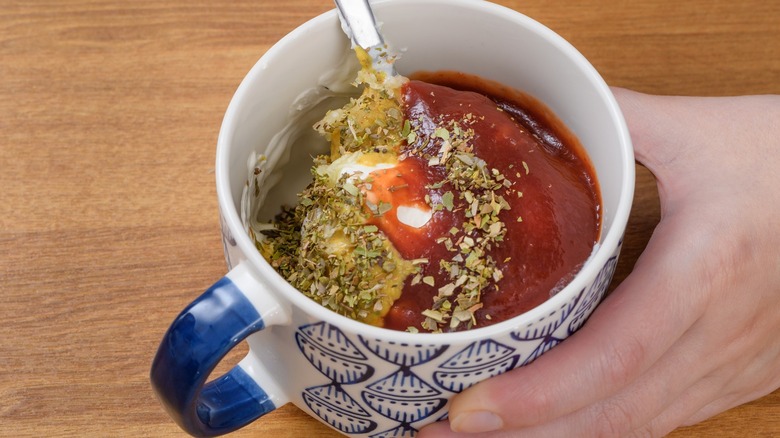 Person mixing ketchup-based marinade in cup