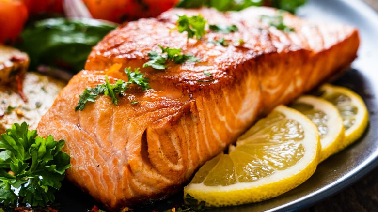 Grilled salmon on plate with lemon and vegetables.