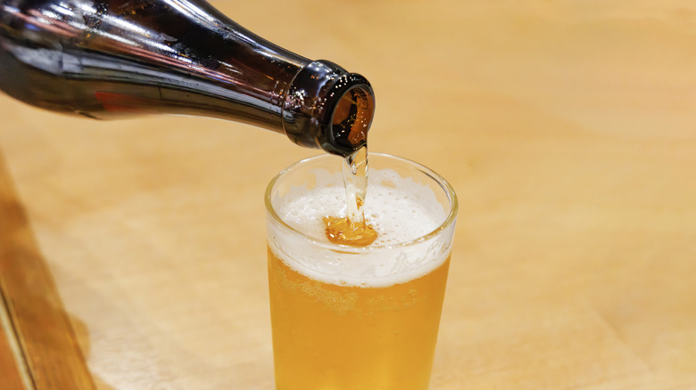Cold golden beer being poured into glass.