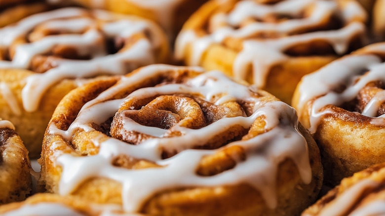 Cinnamon rolls on tray with frosting drizzled over the top