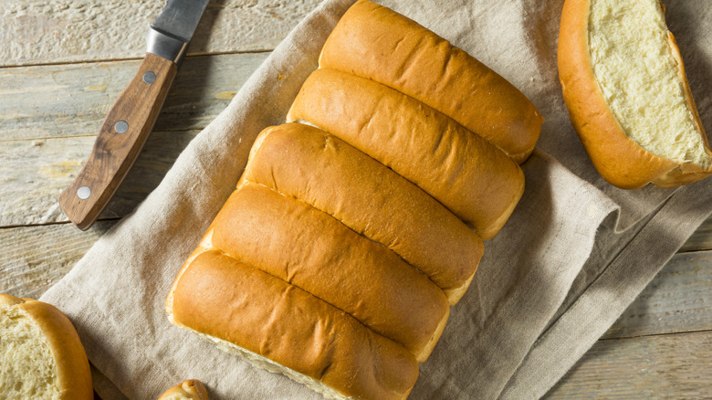 White hot dog buns on a towel on a wood countertop