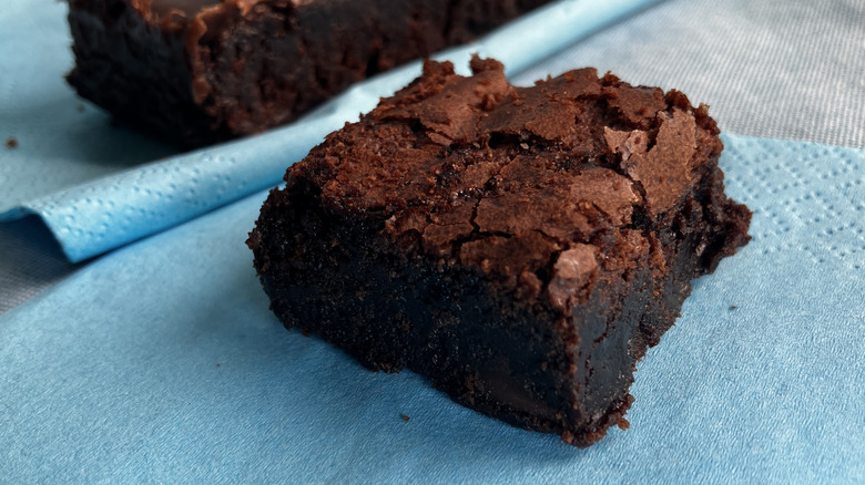 close up of chocolate brownie on blue napkin with another brownie in the background