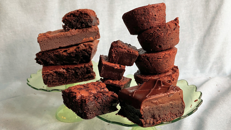 Two stacks of brownies of various shapes and sizes balanced on green cake stands.