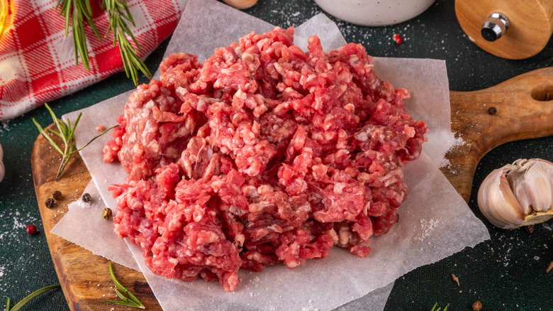 Raw beef mince on parchment paper-lined wooden cutting board