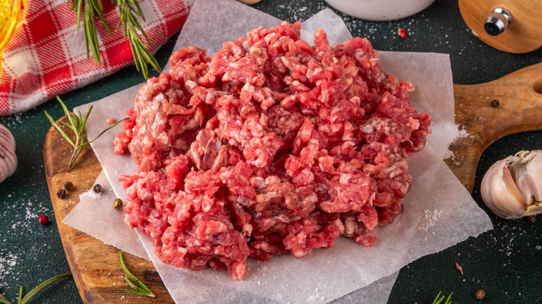 Raw beef mince on parchment paper-lined wooden cutting board