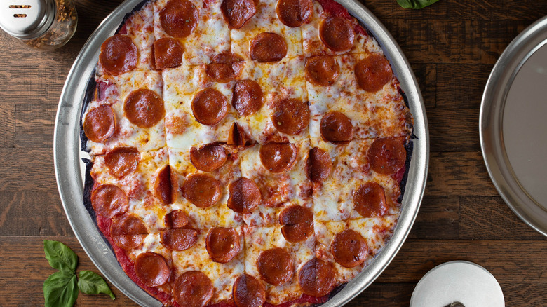 tavern-style pepperoni pizza in a metal pan on a wooden table