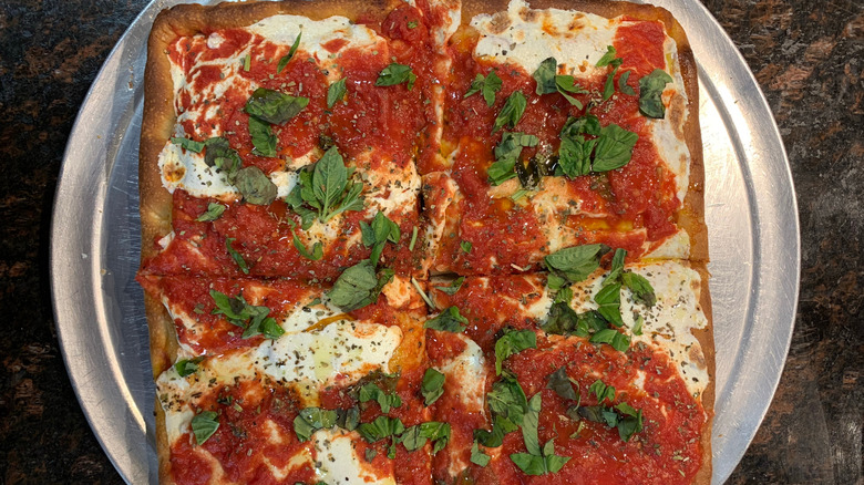 Fresh, fluffy Sicilian style pizza topped with basil, tomato sauce and fresh mozzarella
