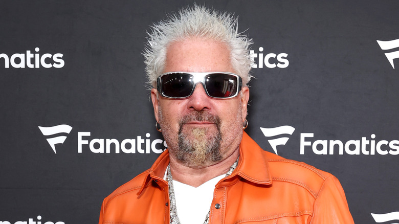 Guy Fieri wearing sunglasses and orange jacket
