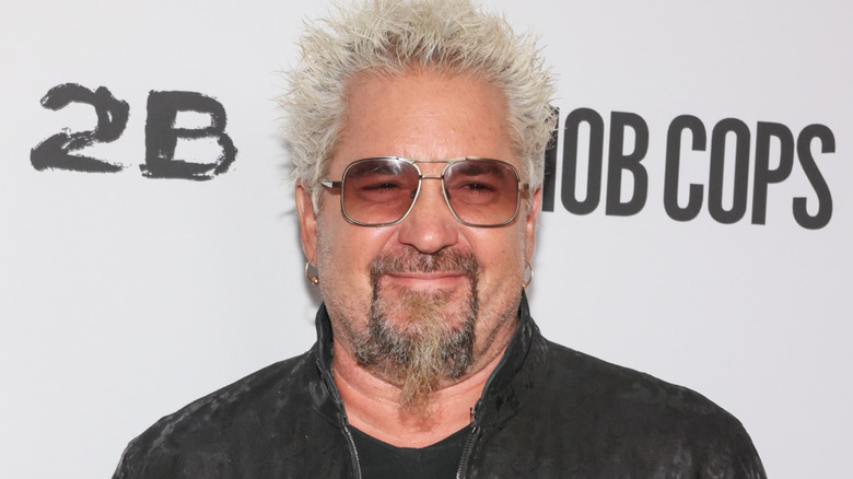 Guy Fieri smiling while wearing sunglasses at a movie premiere