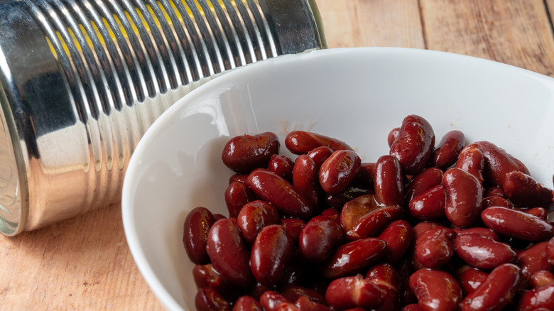 A bowl of beans next to an unlabeled metal food can