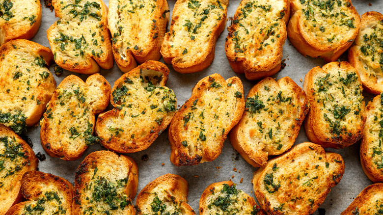 Crispy pieces of garlic bread with good browning and herbs on them