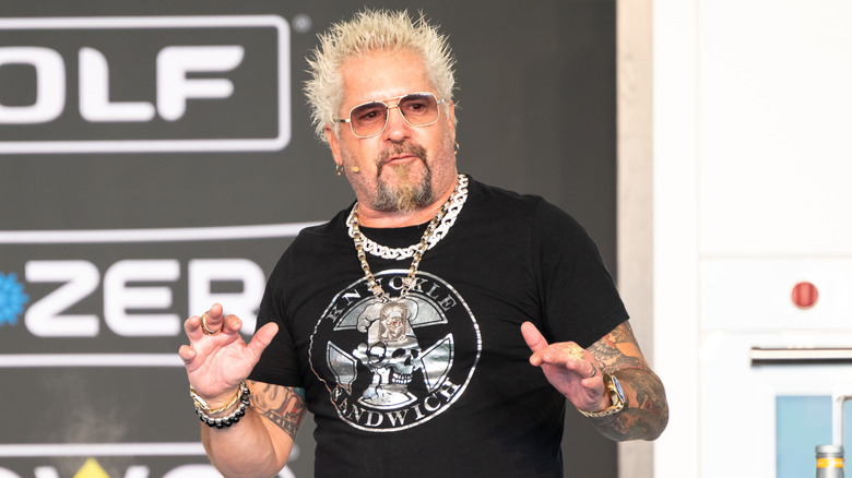 Guy Fieri on stage during a cooking demonstration at an event
