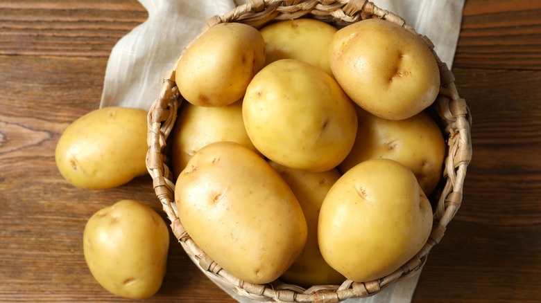 Basket of raw potatoes on a wooden surface