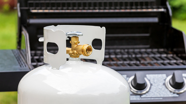 Propane tank sitting in front of a grill