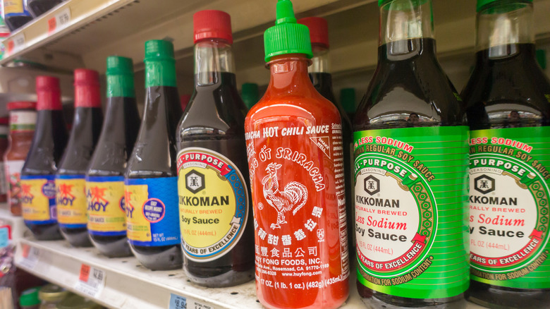 A shelf of soy sauces and sriracha  at a grocery store