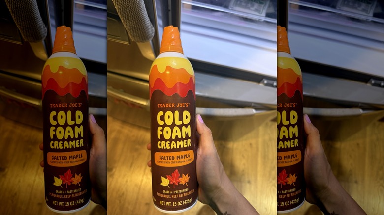 Hand holding Salted Maple Cold Foam Creamer from Trader Joe's in their kitchen.