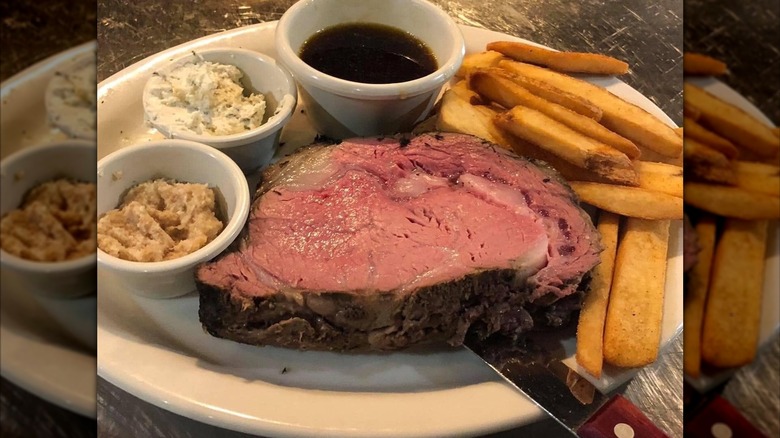 Large slice of prime rib at Mike's Place restaurant served with two kinds of horseradish, au jus and french fries.