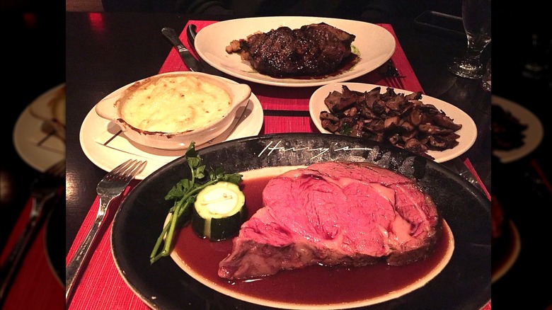 Table of plates including prime rib, steak, and sides at Harry's Savoy Grill.