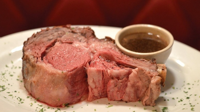 A 48 ounce pink prime rib served on plate with side of au jus at Runyon restaurant.