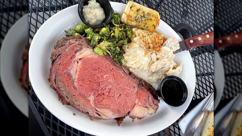 Prime rib dinner served with Brussel sprouts and mashed potatoes on patio table at Teton House restaurant.