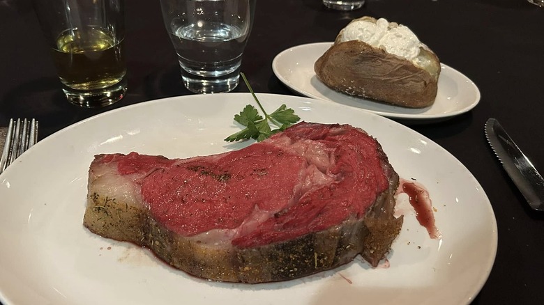 Rare prime rib served with baked potato at St Elmo Steak House