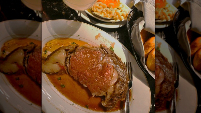 Plate of juicy prime rib next to cocktail and side of macaroni and cheese at The Prime Rib Louisiana