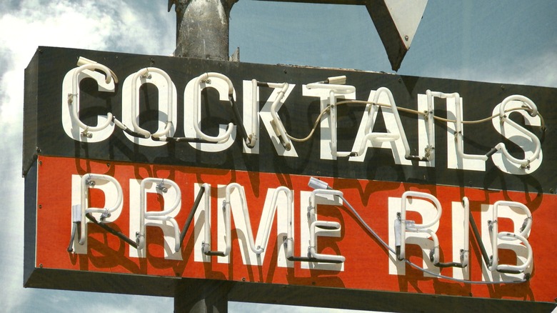 aged and worn vintage neon road sign for cocktails and prime rib