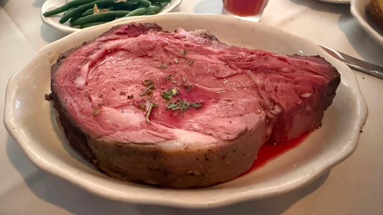 A rosy pink 32 ounce slice of Kreis Steakhouse's prime rib served with green beans.