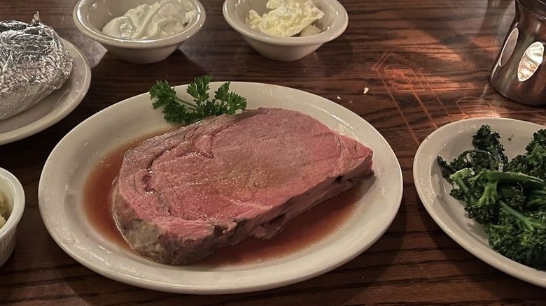 A prime rib steak served with a foil-wrapped baked potato and a plate of broccoli at Brother Sebastian's restaurant.