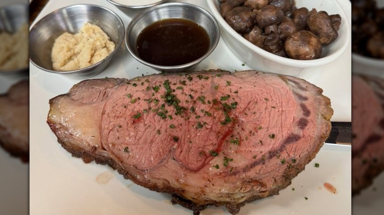 The Crain Lounge and Kitchen's smoked prime rib on plate served with horseradish, au jus, and mushrooms.