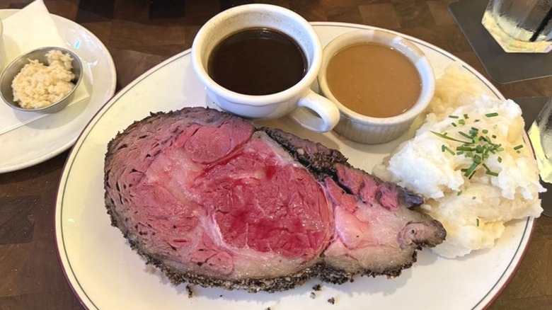 Laurenzo's restaurant prime rib served with horseradish, au jus, gravy, and mashed potatoes on plate.