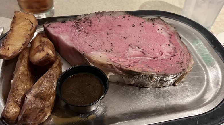 Queen's Cut Prime Rib with broiler potatoes and au jus on metallic tray at Schwarz's Supper Club.