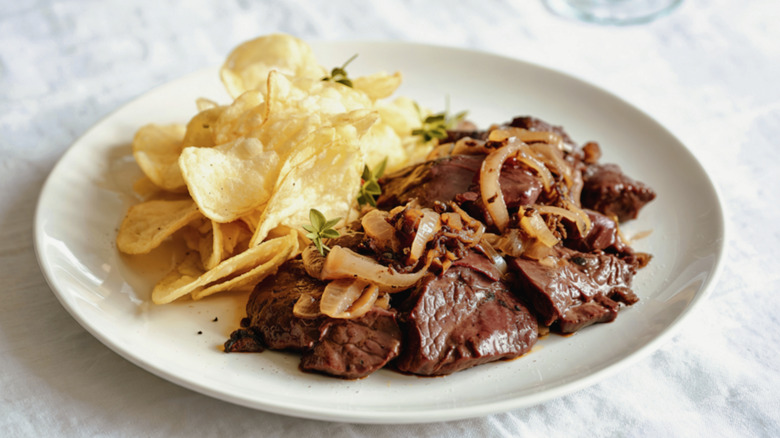 Cooked beef liver with onions and a side of potato chips
