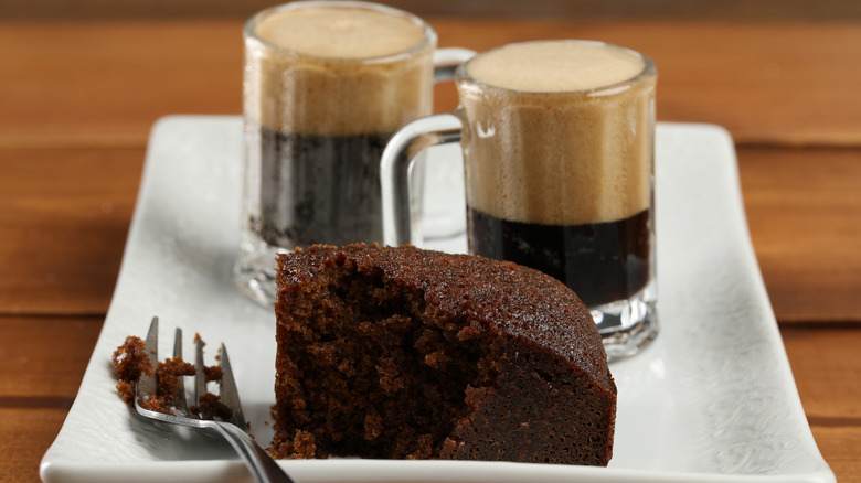 two mugs of stout beer with a slice of chocolate cake