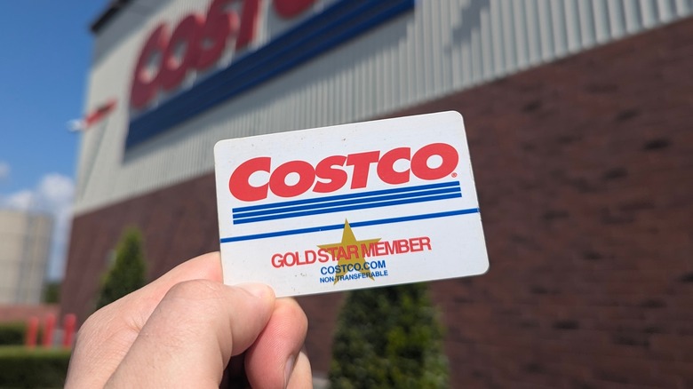 A hand holding a Costco Gold Star Member card