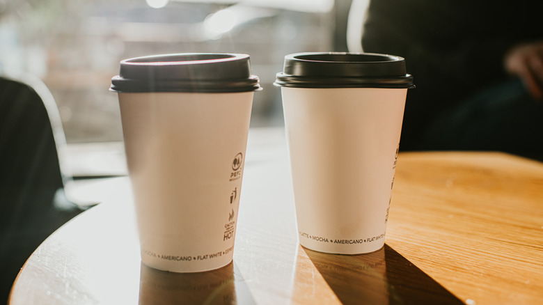 Two cups of to-go coffee on a wooden surface