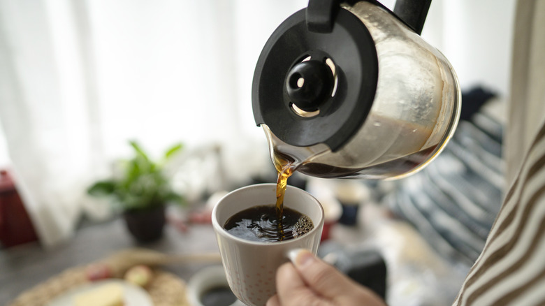 Person pouring coffee from pot into cup