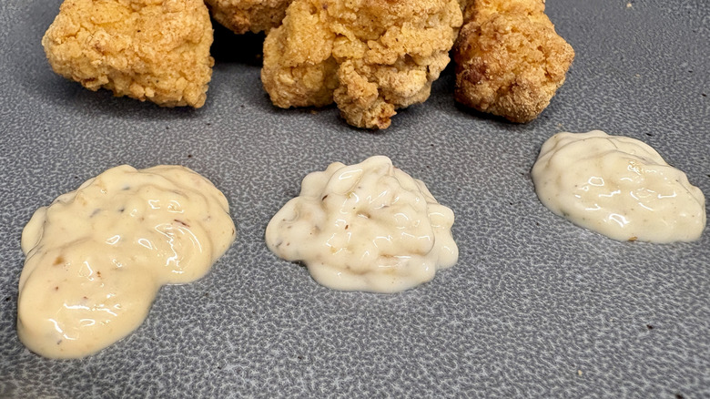 Close-up of sauces on plate with chicken nuggets in background