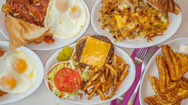An overhead shot of a table of dishes at Mickey's Diner by Willy, featuring eggs, French toast, and a cheeseburger with fries