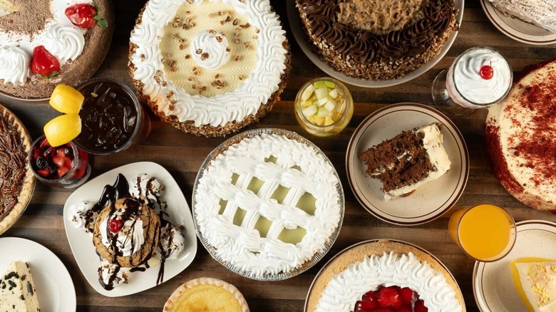 An overhead shot of a table full of whole pies, plated slices of pie and cake, and drinks at House of Pies