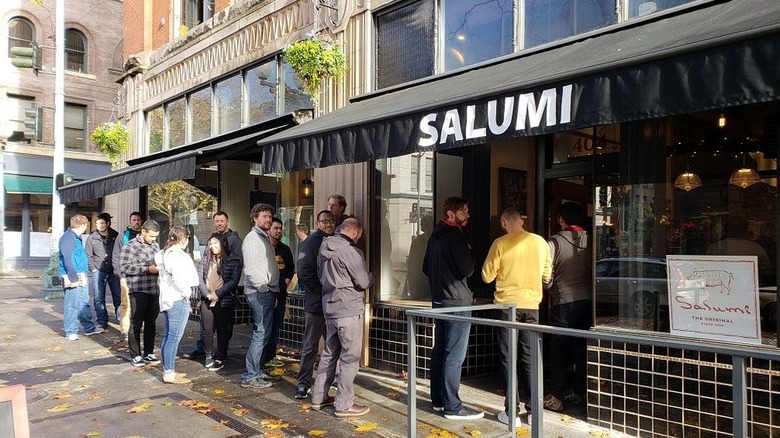 Exterior of Salumi in Seattle, with line of customers