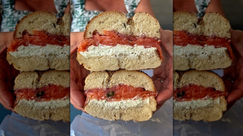 Hands holding two halves of a stuffed bagel