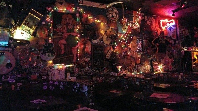 Dimly lit interior of a dimly lit bar with random decor and string lights covering the walls and three curved booths that are covered in stickers