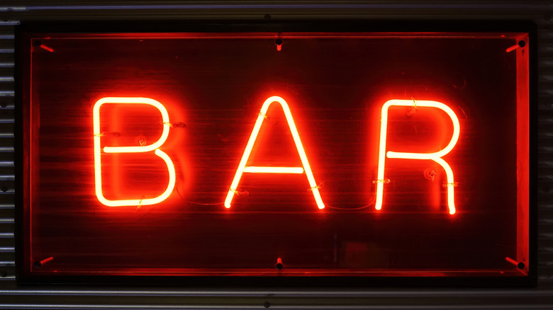 Close-up of a red neon sign set on a black background that says "bar"